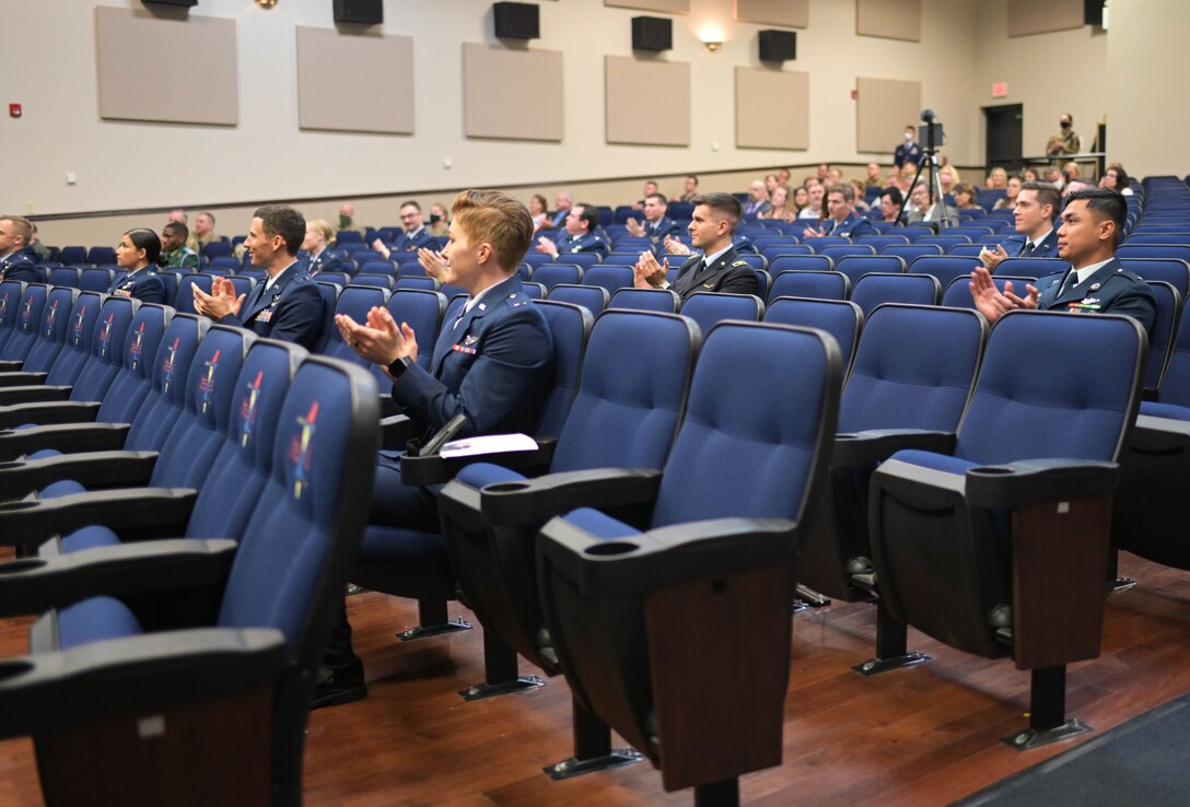 U.S. Air Force and international student pilots from class 21-02 clap for one of their fellow classmates receiving a diploma Nov. 13, 2020, on Columbus Air Force Base Miss. As a result of COVID-19 restrictions the graduation was live streamed to Facebook on the Columbus AFB page for viewers not in attendance. (U.S. Air Force photo by Senior Airman Jake Jacobsen)