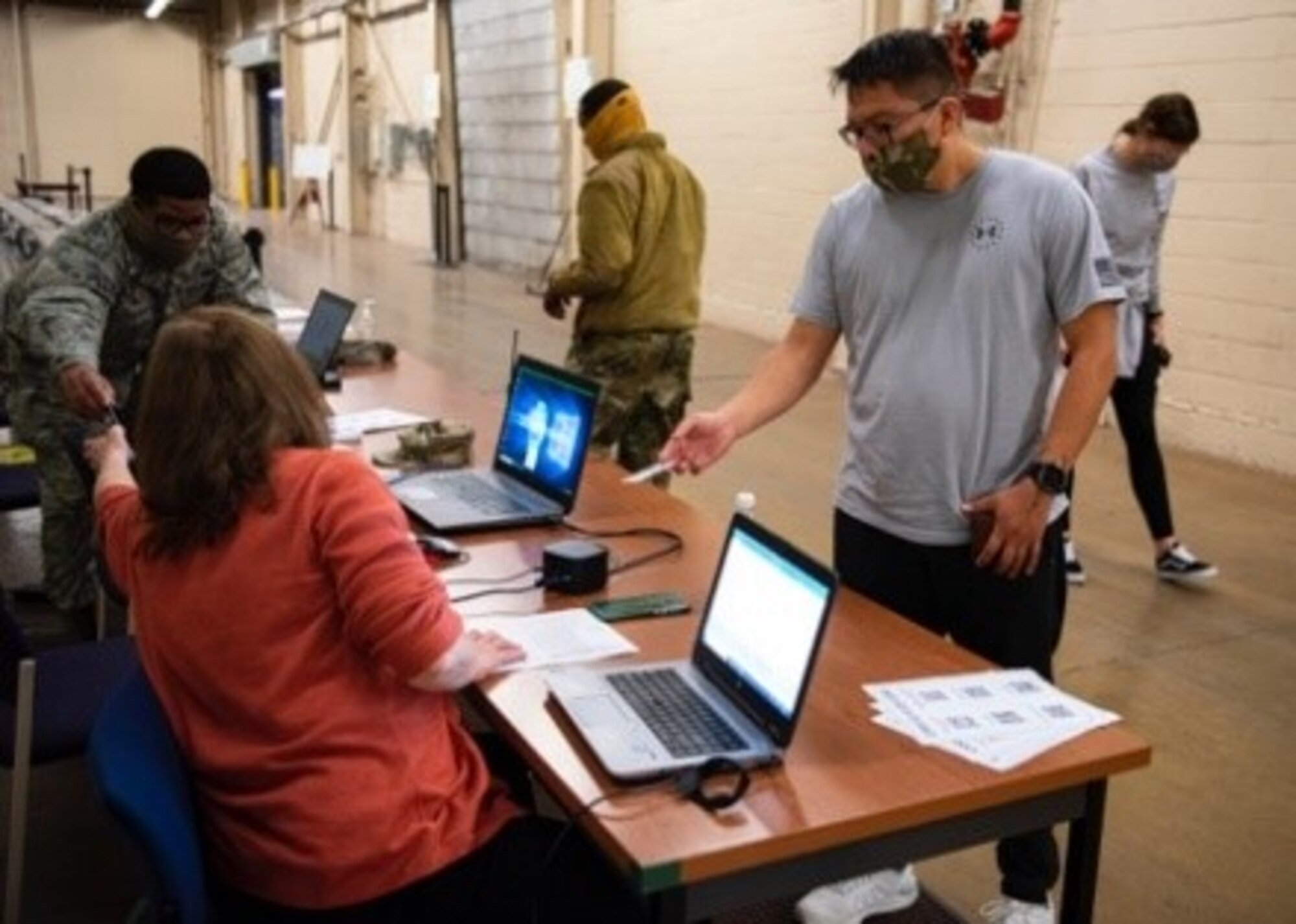 An Airman hands their ID card to in-process.