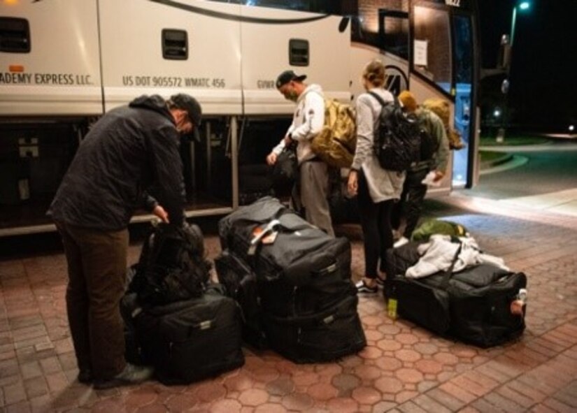 Airmen unload luggage from a bus.
