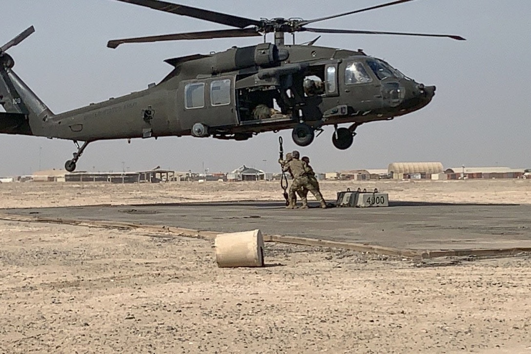 Soldiers sling load a helicopter.