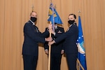 Two Airmen pose for a photo with the squadron's guidon flag