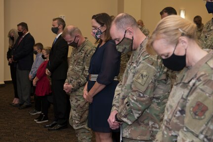 An audience bows their head in prayer