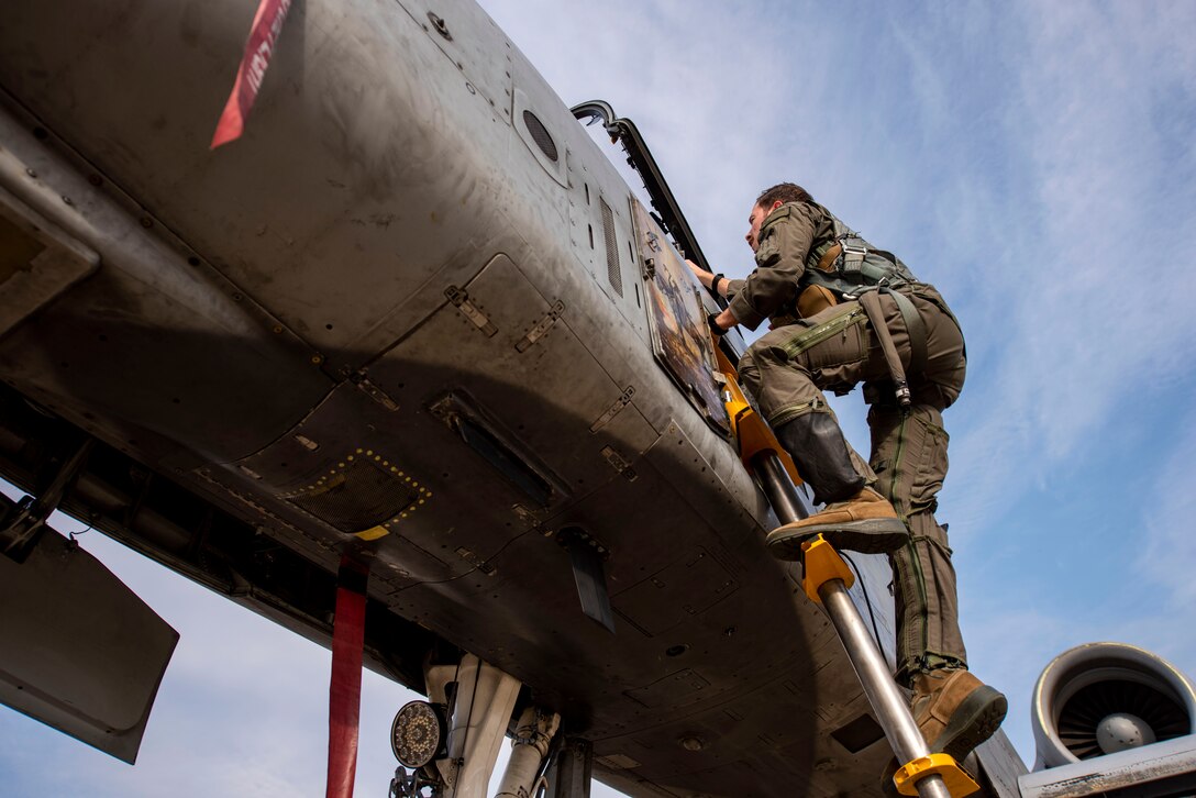 A pilot climbs into the cockpit of an A-10
