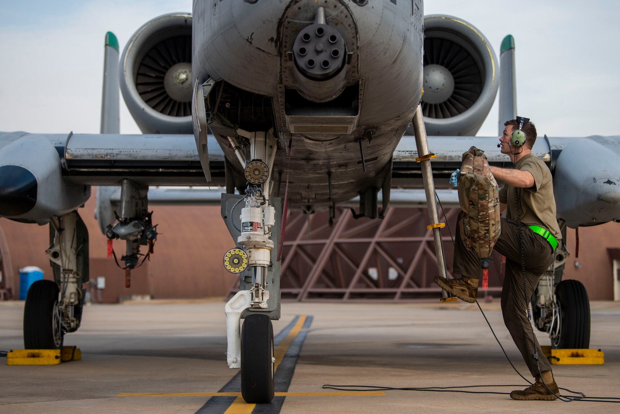 A maintainer climbs the ladder to an A-10