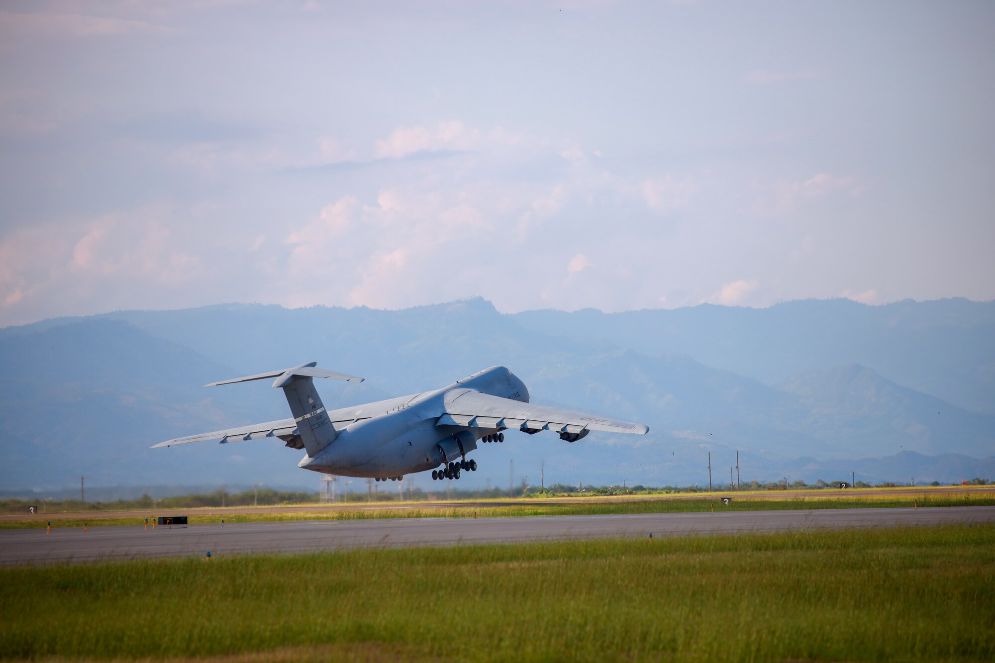A very large grey airplane takes off from a run way.