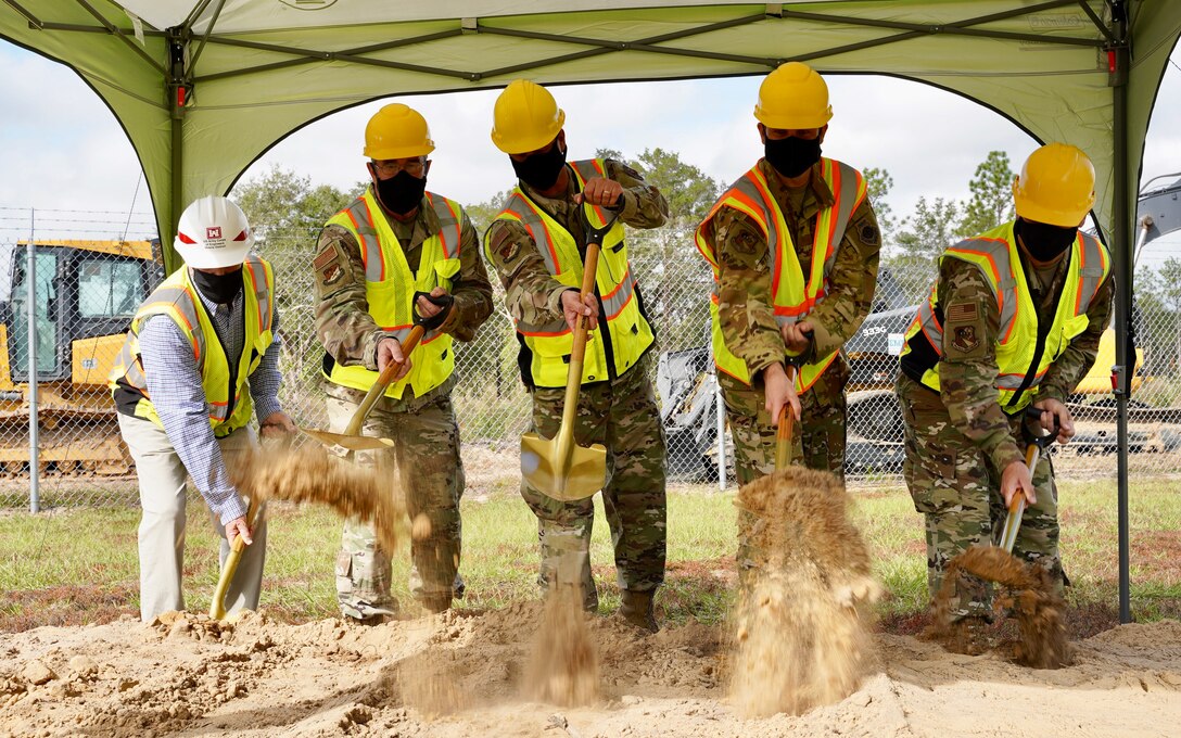 Photo of five people shoveling dirl