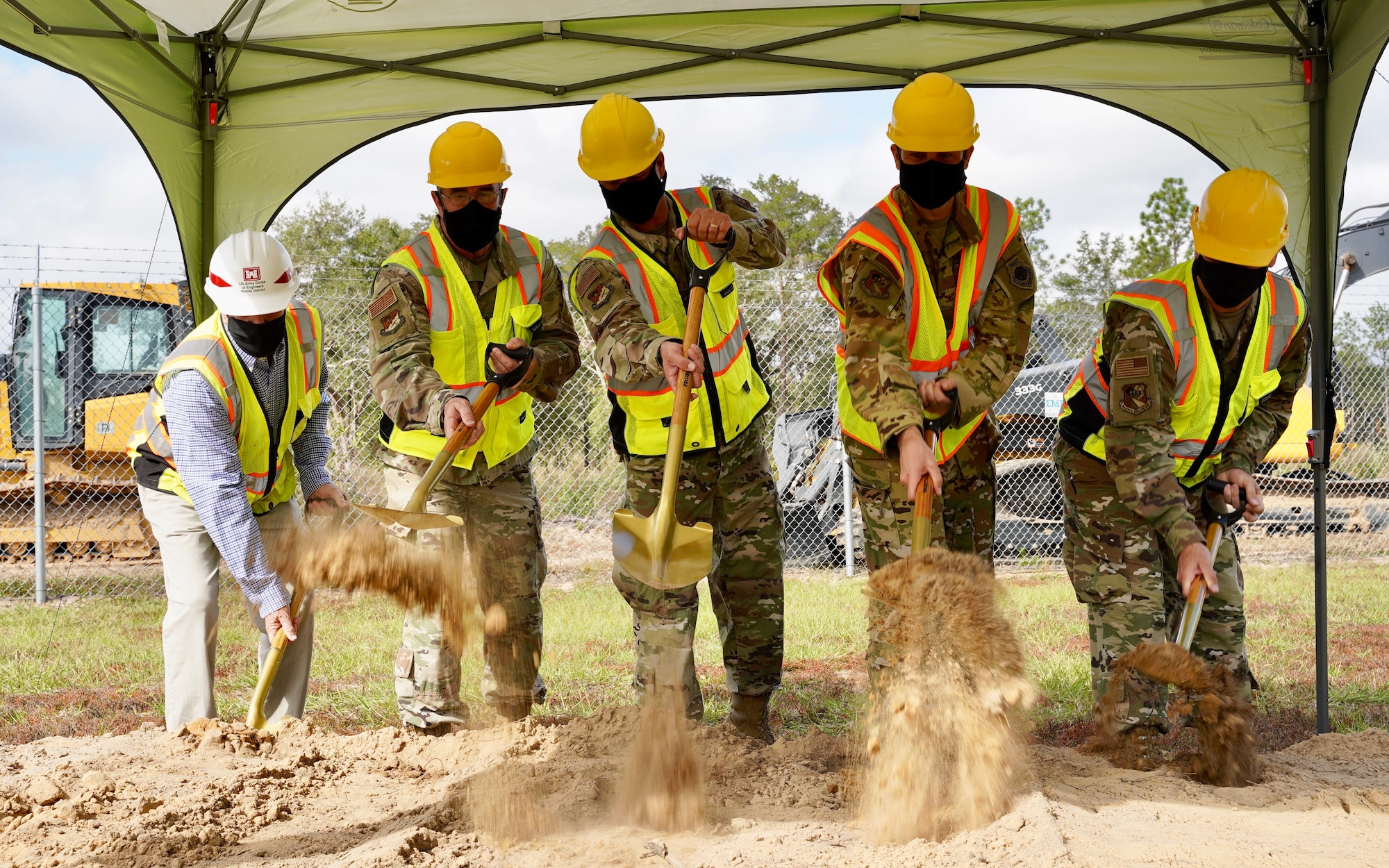 Photo of five people shoveling dirl