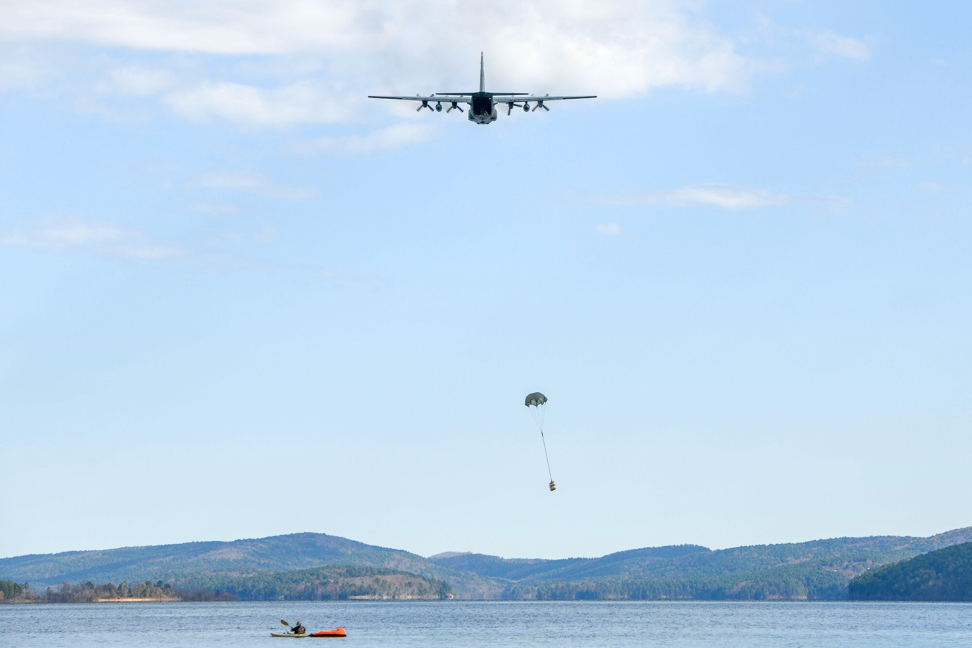 Plane flying over lake dropping small package