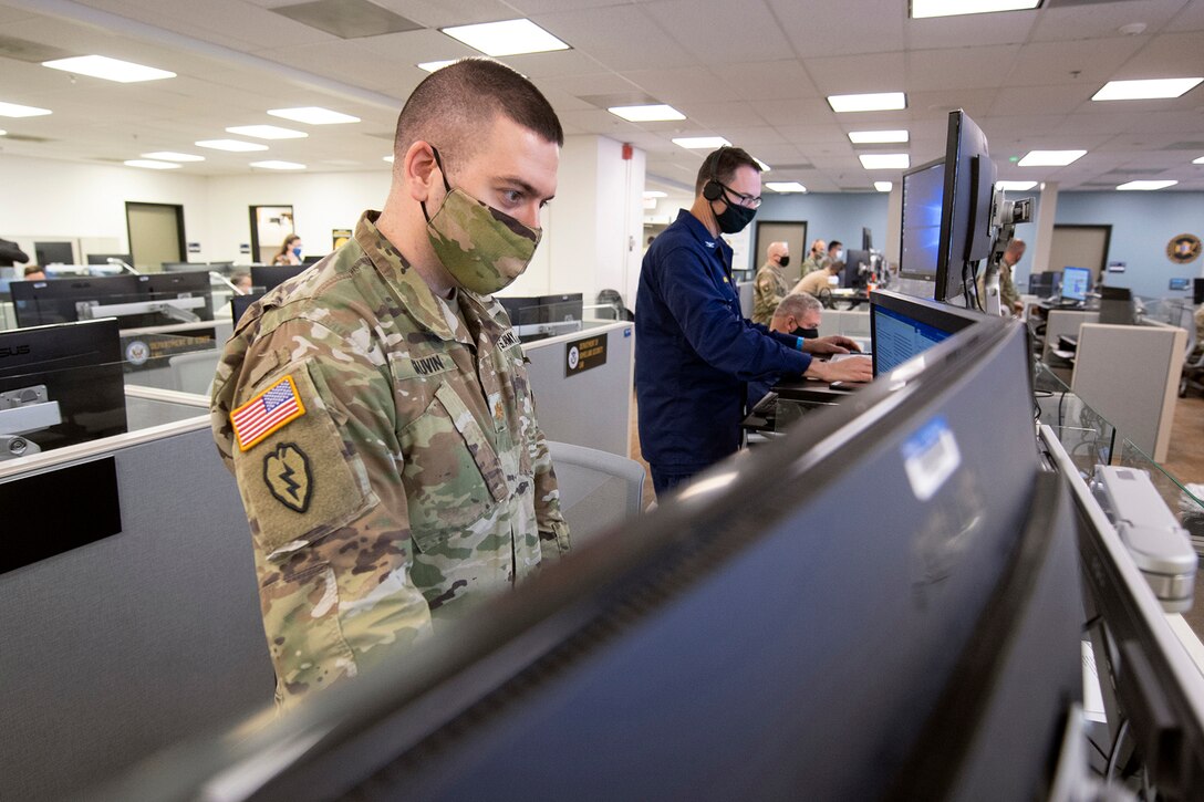 A service member focuses on a computer monitor.