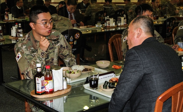 A KATUSA soldier talks with a member of South Korea's National Assembly Defense Committee during lunch.