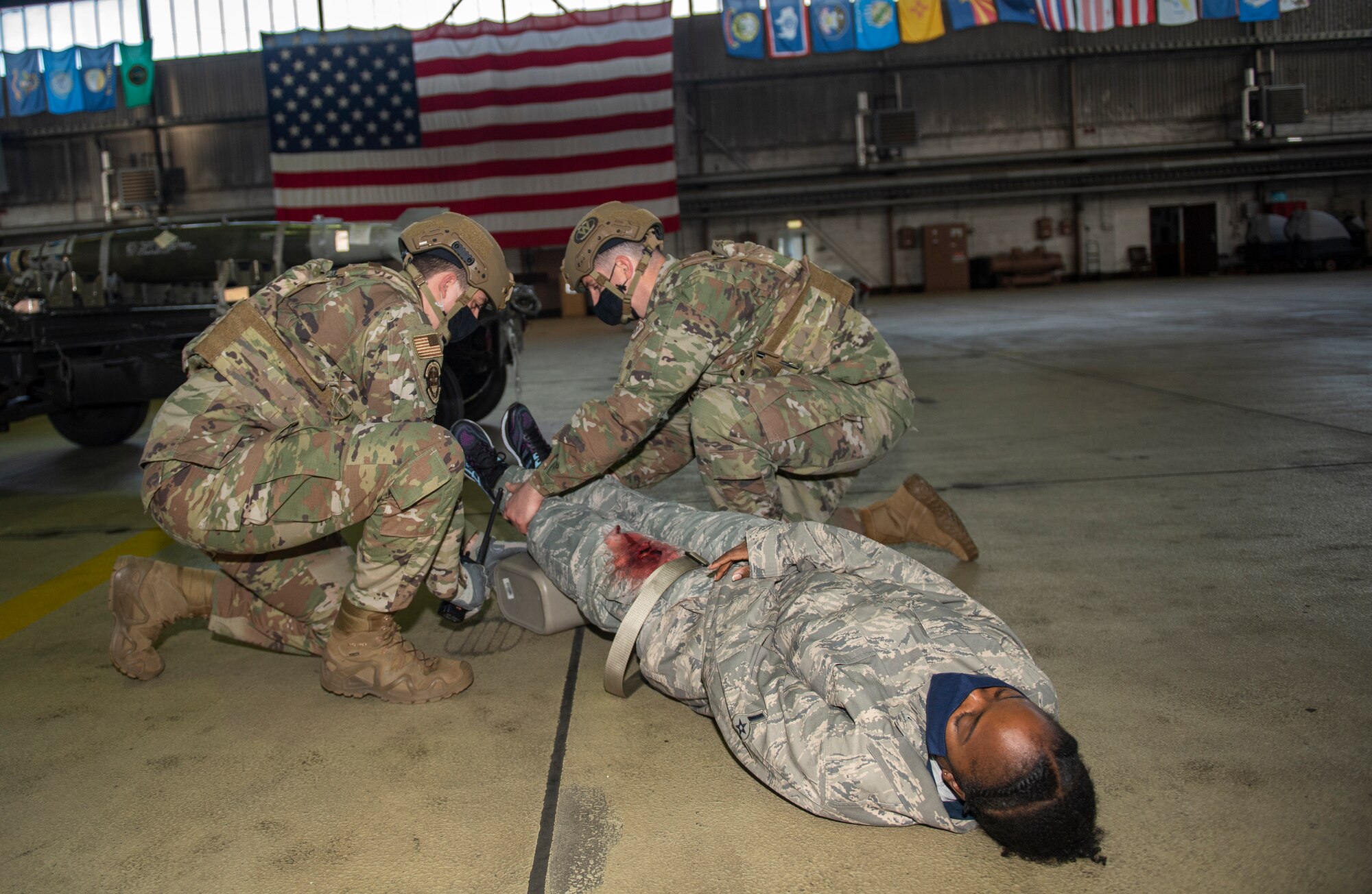U.S Air Force Tech. Sgt. Brian Fossum, 52nd Security Forces Squadron flight sergeant, and Tech. Sgt. Donald Miller, 52nd SFS reports and analysis NCOIC, tend to an Airman wounded in an active shooter drill at Spangdahlem Air Base, Germany, Nov. 16, 2020. Airmen from various squadrons volunteered to have moulage makeup applied to make the simulation more realistic for first responders on scene. (U.S. Air Force photo by Senior Airman Ali Stewart)