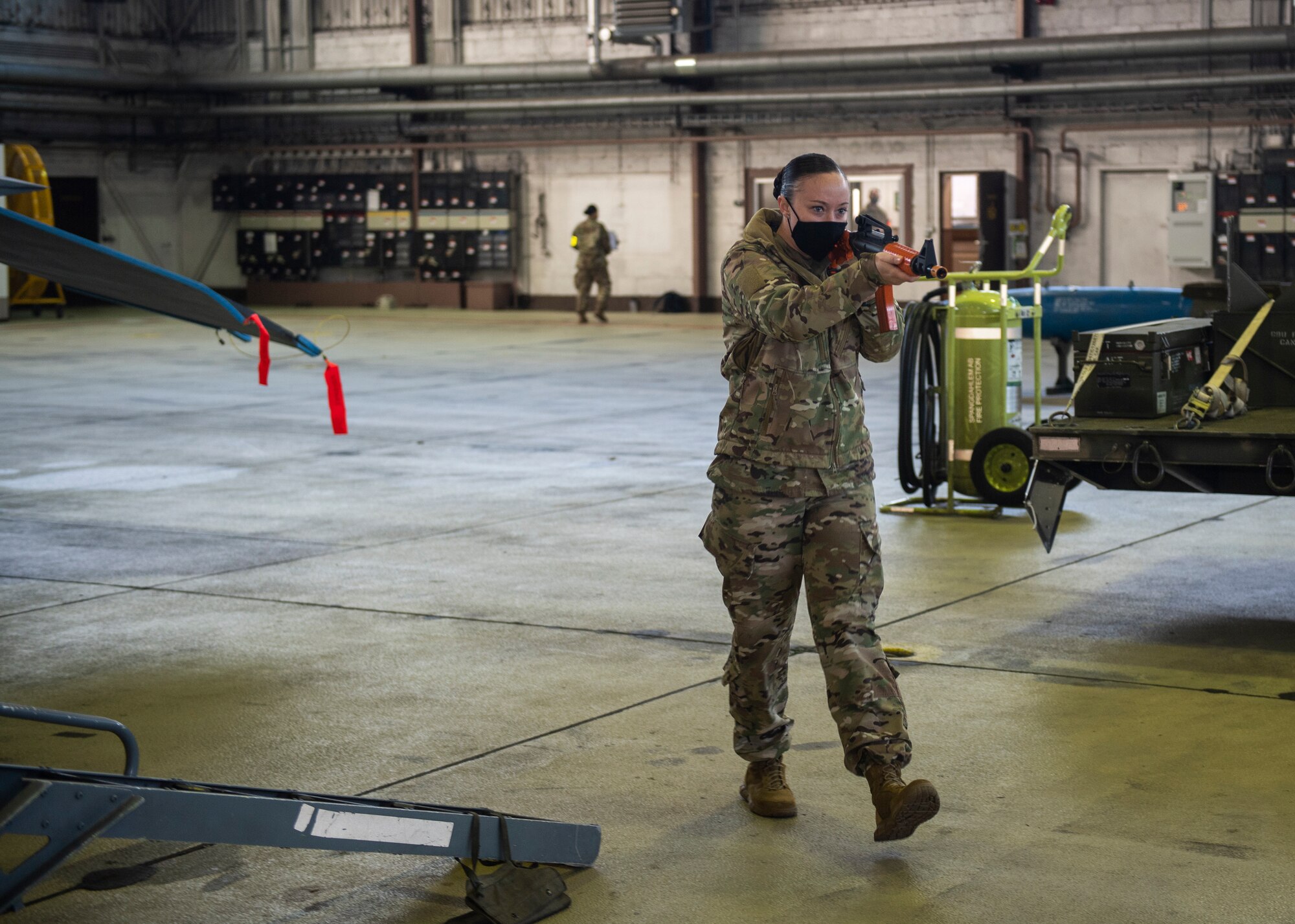 U.S. Air Force Staff Sgt. Shealyn Kunze, 52nd Security Forces Squadron resource protection NCOIC, aims a simulation weapon at a victim during an active shooter exercise at Spangdahlem Air Base, Germany, Nov. 16, 2020. Kunze portrayed an active shooter situation in which a distressed individual wounded and killed fellow Airmen at Hangar 1. (U.S. Air Force photo by Senior Airman Ali Stewart)
