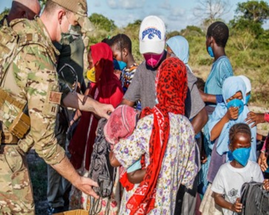 U.S. Air Force Capt. Ian Latham, 475th Expeditionary Air Base Squadron deputy force commander, hands out supplies and a backpack to a family in Magogoni Village at Manda Bay, Kenya, Nov. 6, 2020.