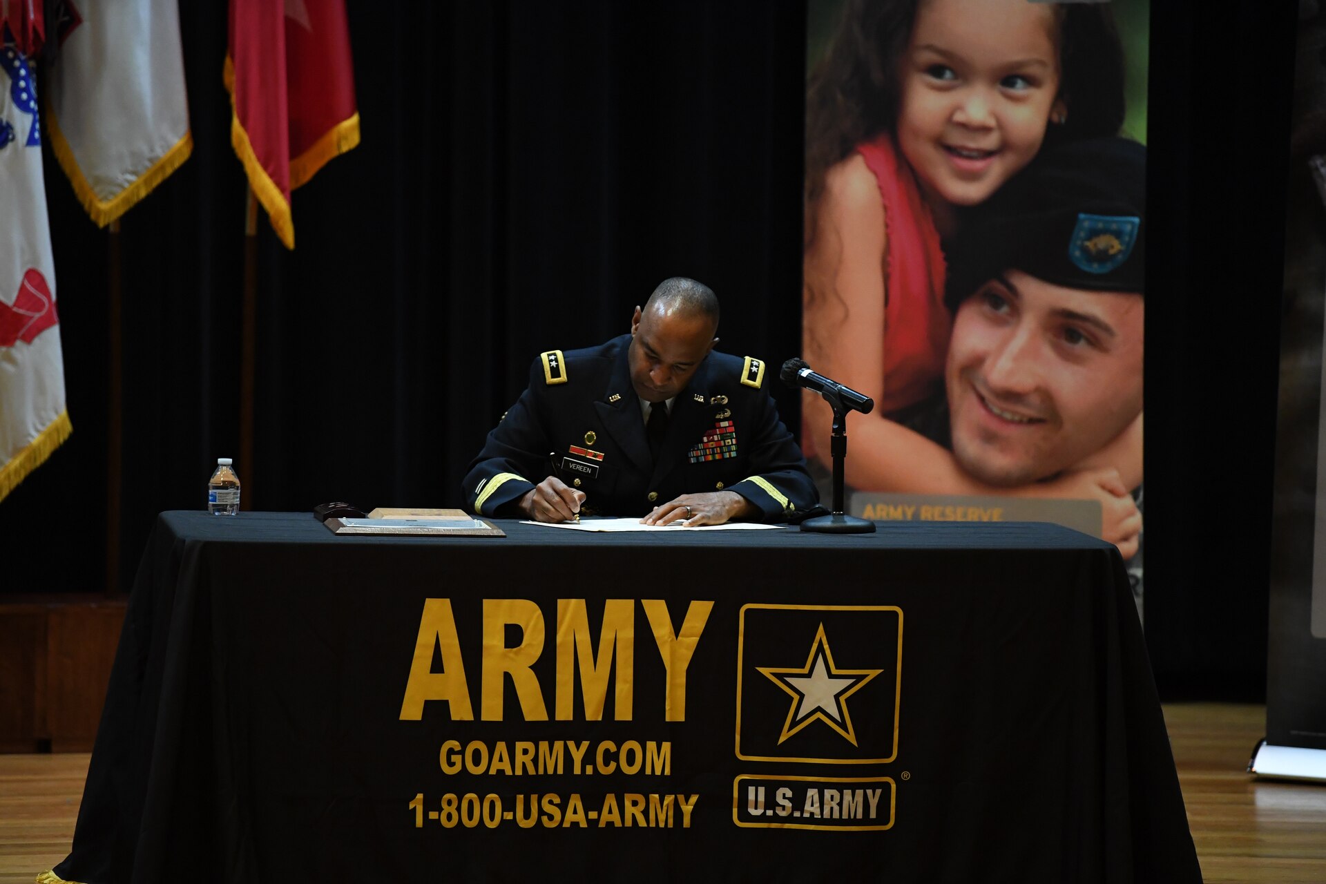 Two men signing contractual agreement on a stage.