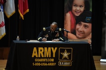 Two men signing contractual agreement on a stage.