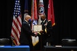 Two men signing contractual agreement on a stage.