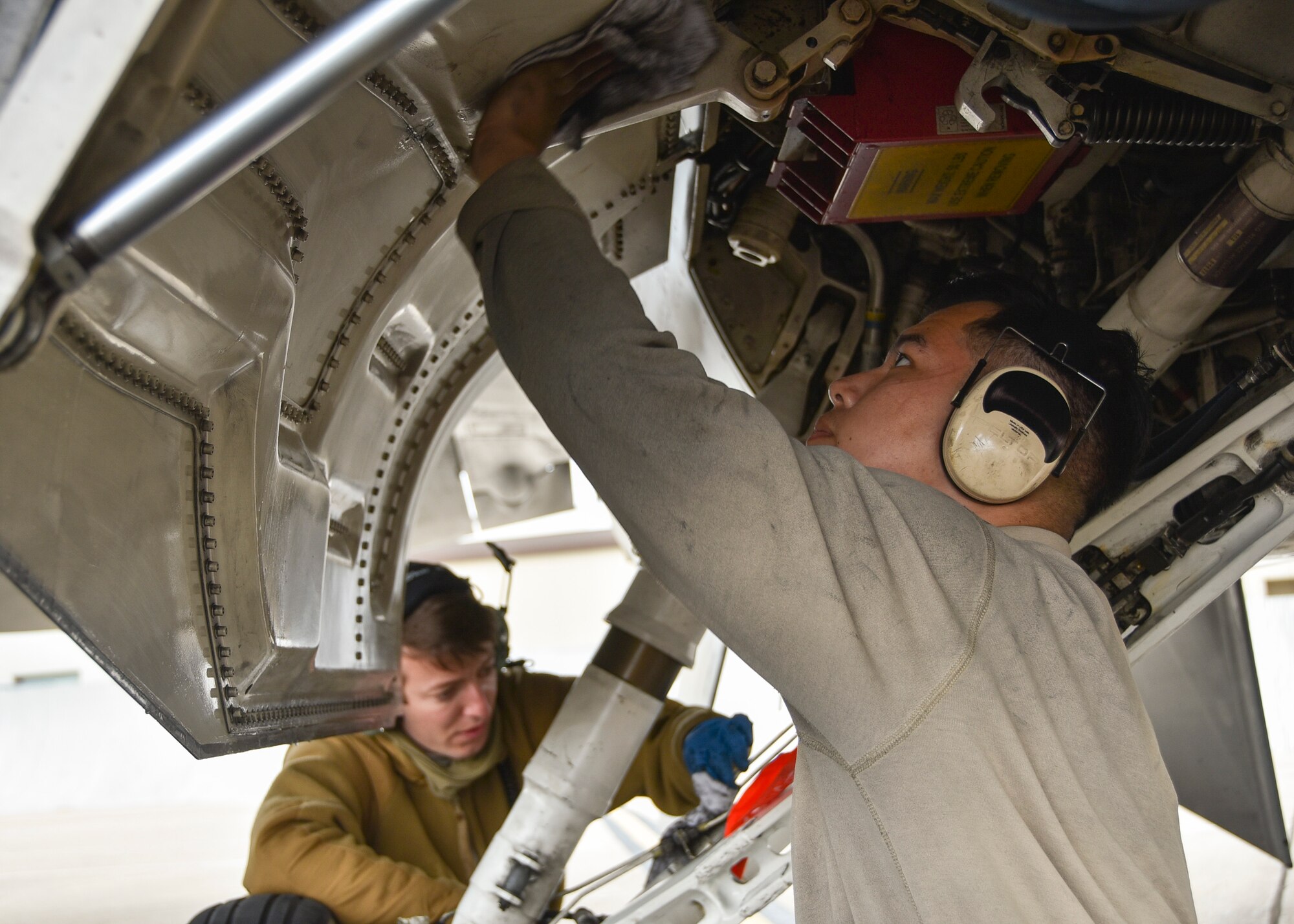 Senior Airman Xavier Murillo and Airman 1st Class Matthew Press, 24th Fighter Squadron crew chiefs, clean under the landing gear bay of an F-16 Fighting Falcon at U.S. Naval Air Station Joint Reserve Base Fort Worth, Texas, Nov. 8, 2020. Crew chiefs are responsible for servicing, launching, recovering, and inspecting aircraft. (U.S. Air Force photo by Senior Airman Kedesha Pennant)