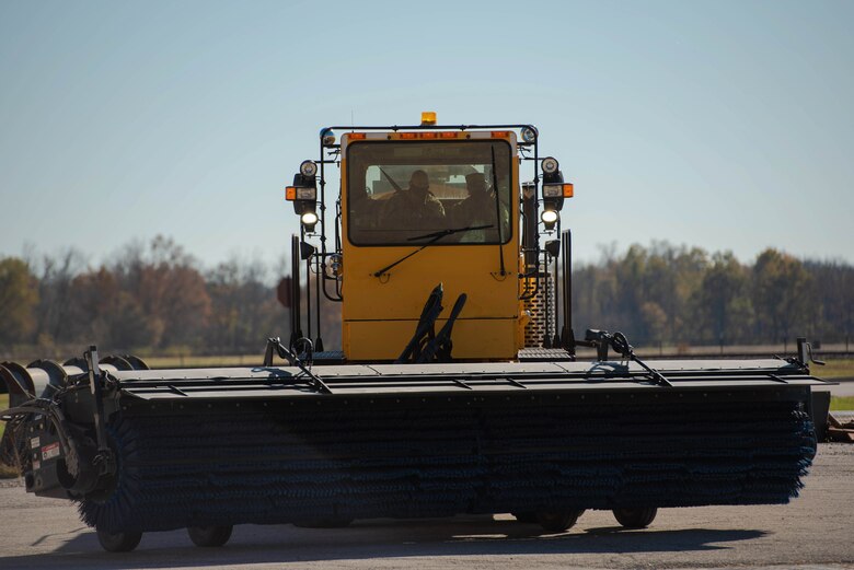 Two Airmen drive a tractor.