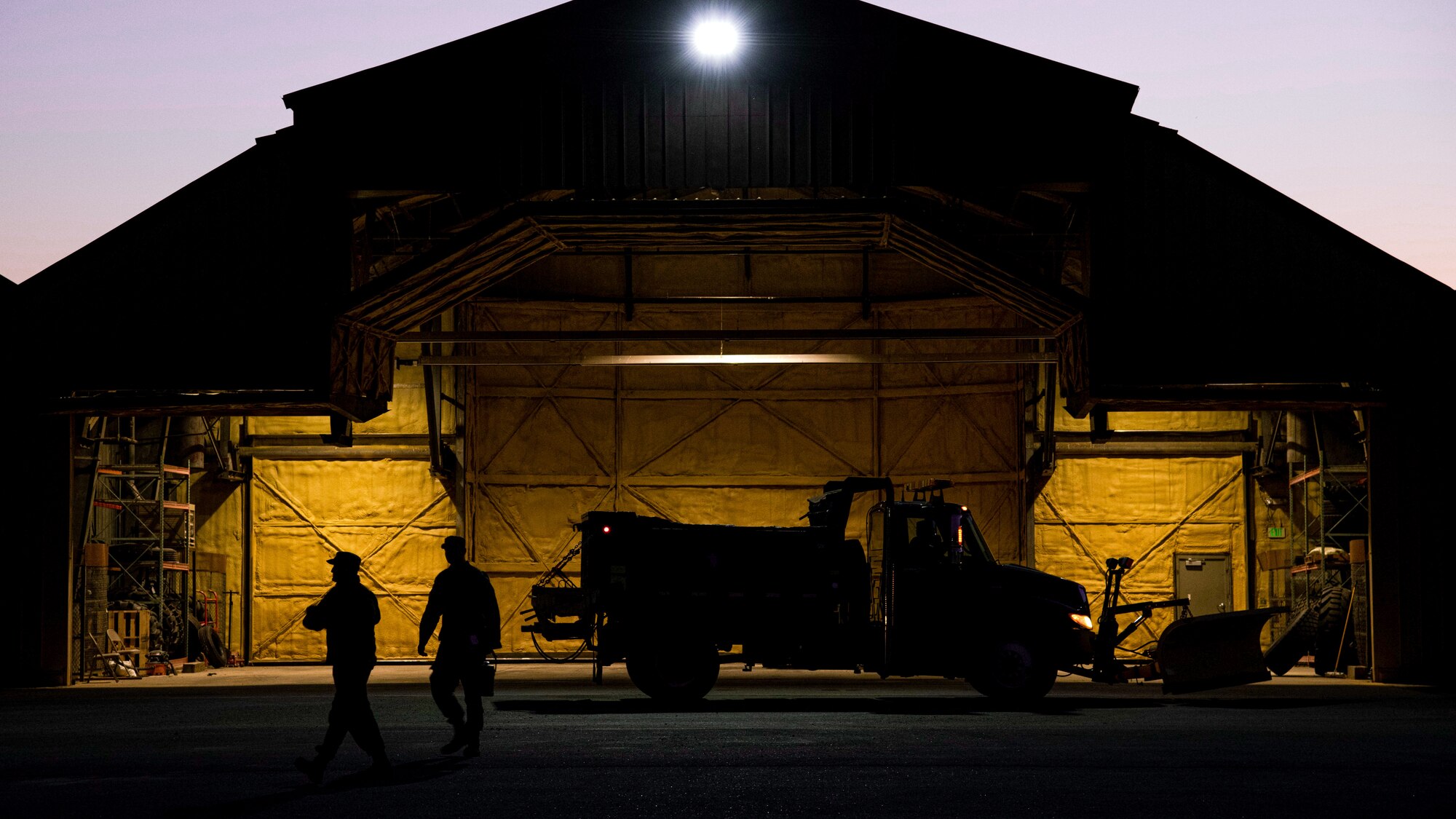 Airmen walk in front of barn at night.