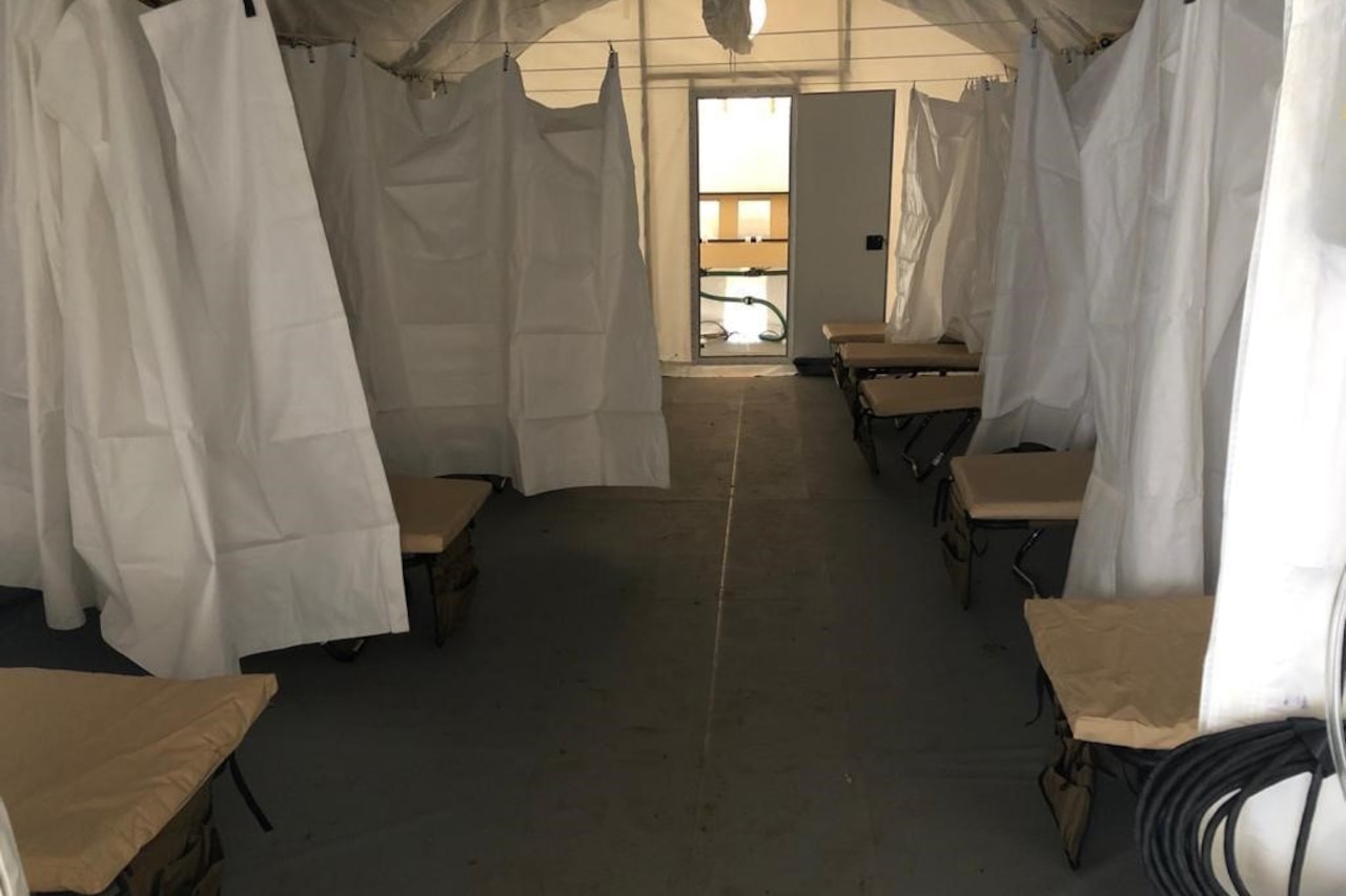 The interior ward of a field hospital is shown.