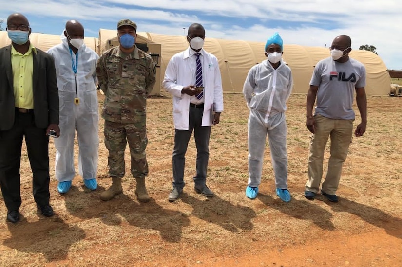 Men in the desert pose in front of a field hospital.