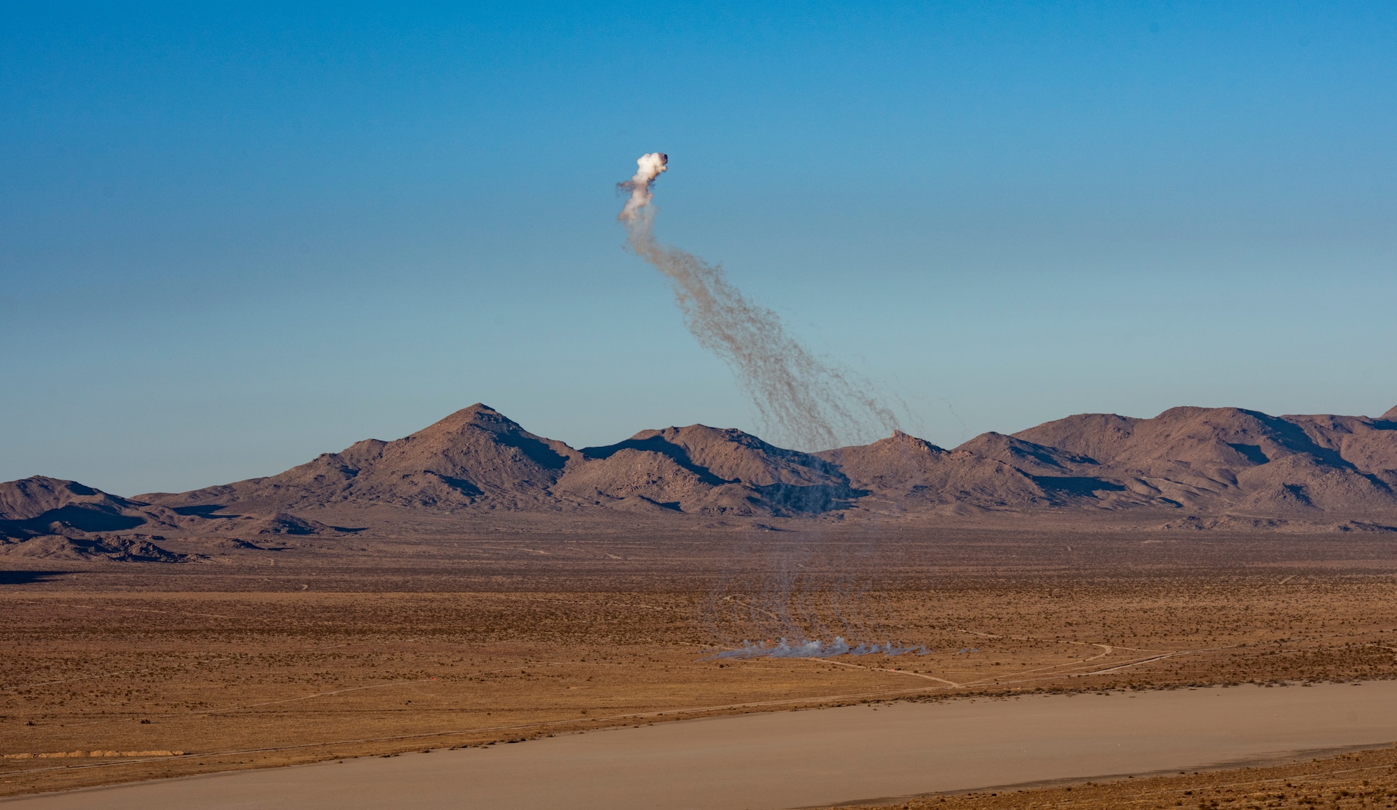 A white phosphorus round detonates in desert.