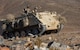 Soldier drives Armored Personnel carrier on hill.