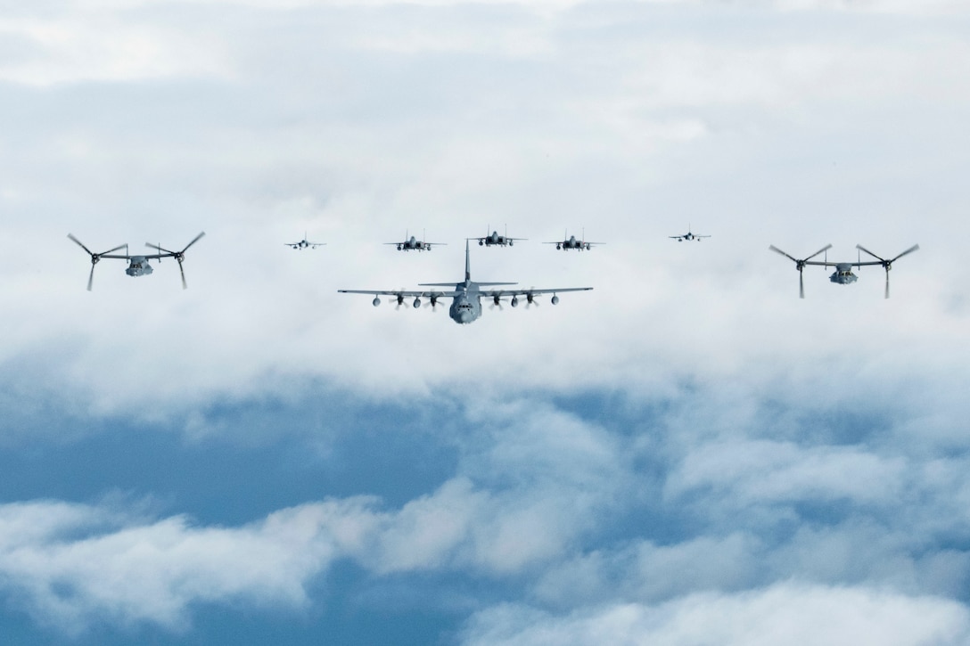 Eight aircraft fly in formation in cloudy blue skies.