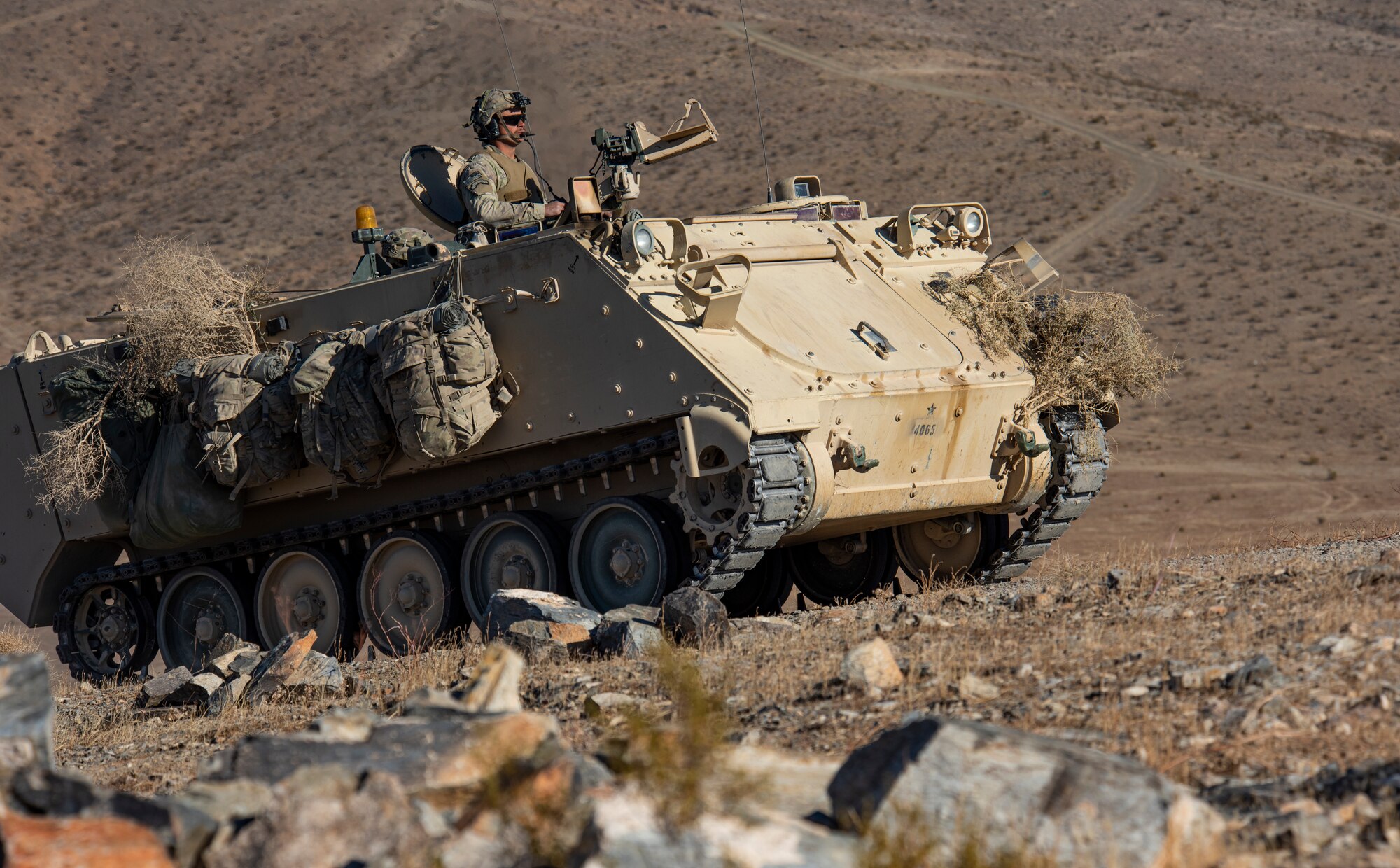 Soldier drives Armored Personnel carrier on hill.