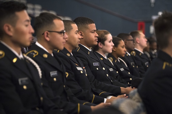 Students in military uniforms sit in rows in an auditorium.