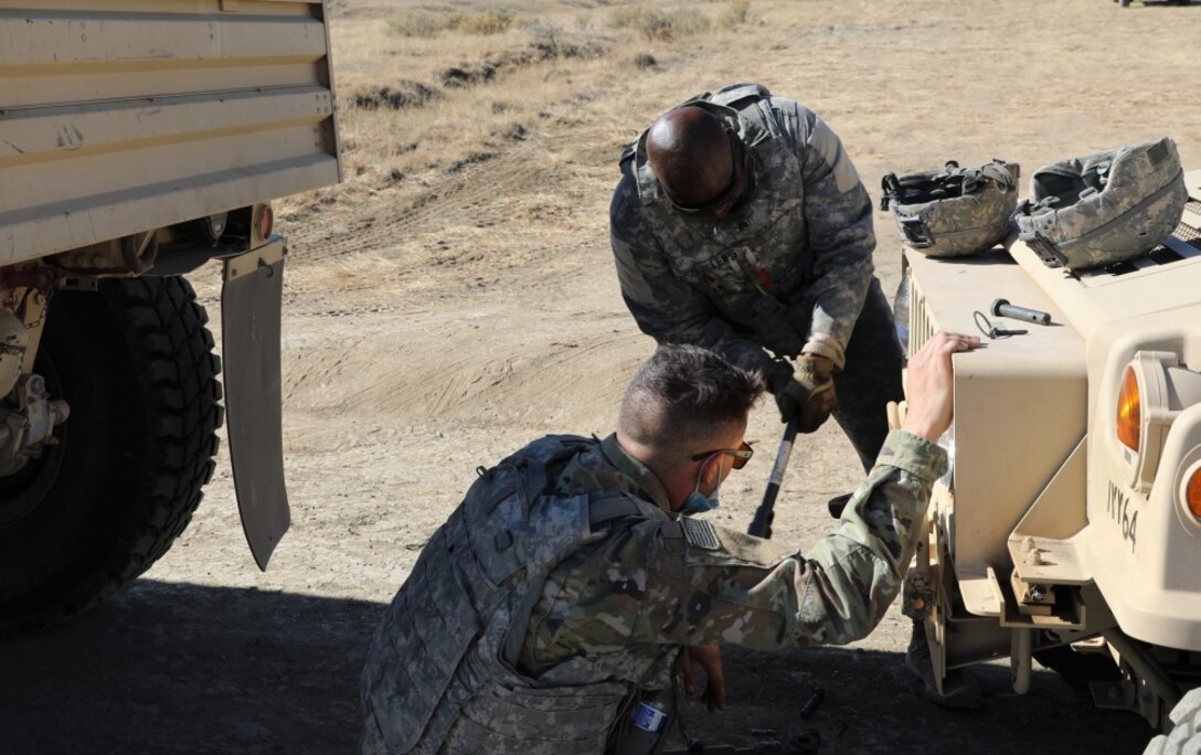 Soldiers perform maintenance on a military vehicle.