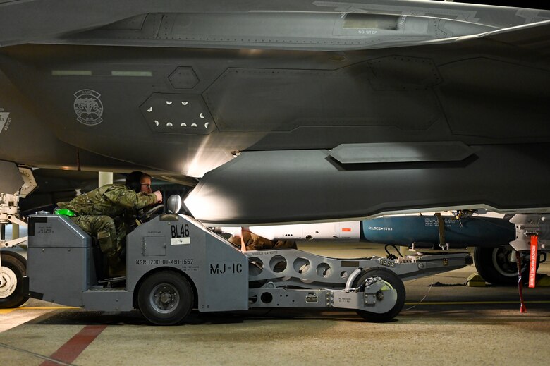 A photo of maintainers loading weapons onto and F-35A Lightning II.