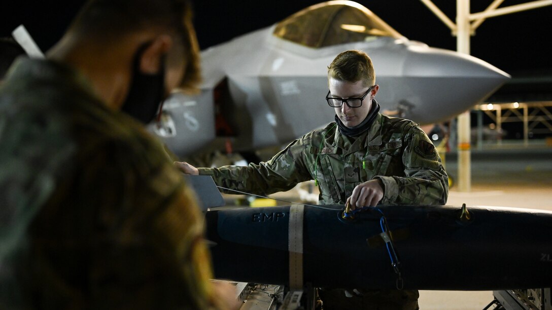 A photo of maintainers loading weapons onto and F-35A Lightning II.