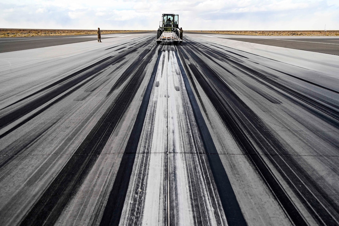 Airmen use a forklift to transport cargo across an aircraft runway.