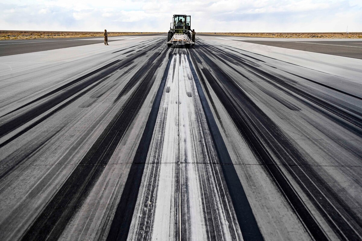 Airmen use a forklift to transport cargo across an aircraft runway.