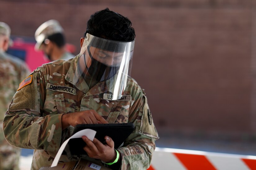 A soldier with personal protective gear takes down information.