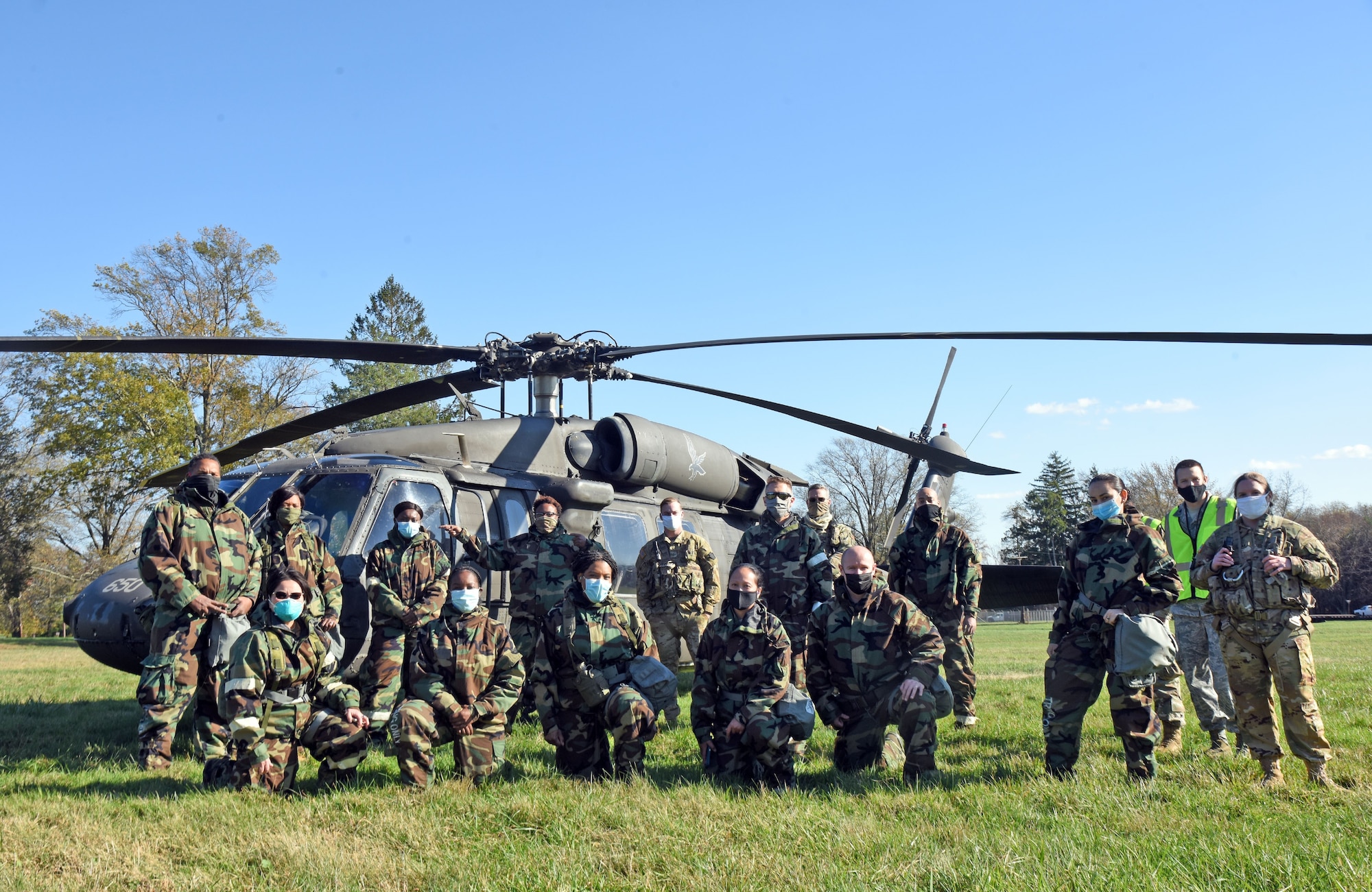 Participants huddle in front of a helicopter.