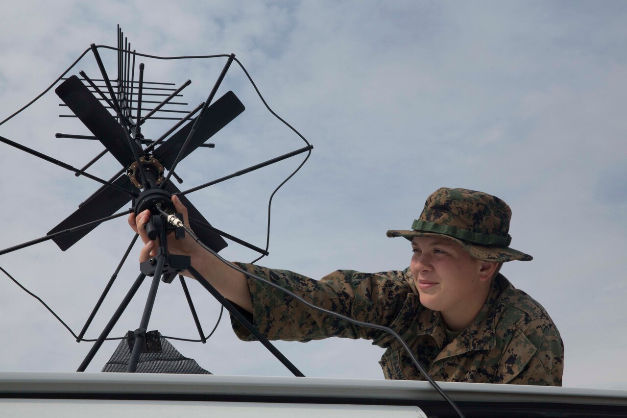 A service member adjusts a satellite communications device.
