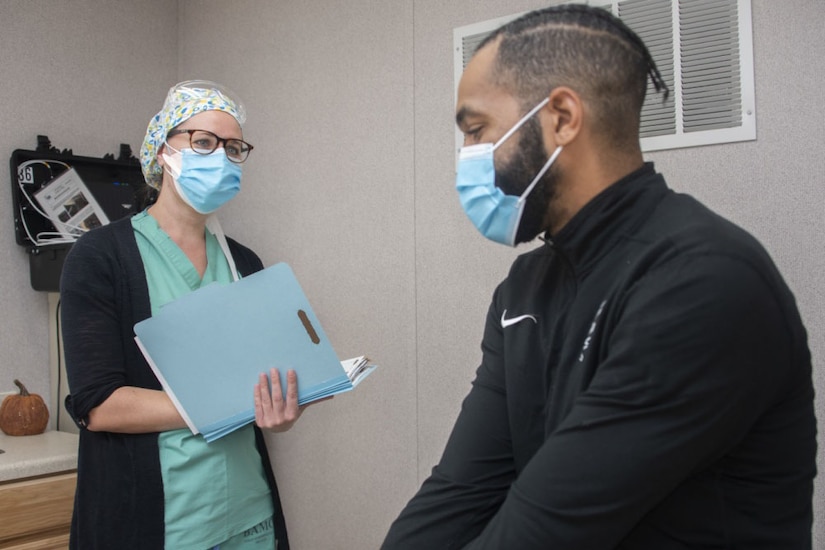 A nurse and research assistant demonstrate patient screening for a vaccine trial.