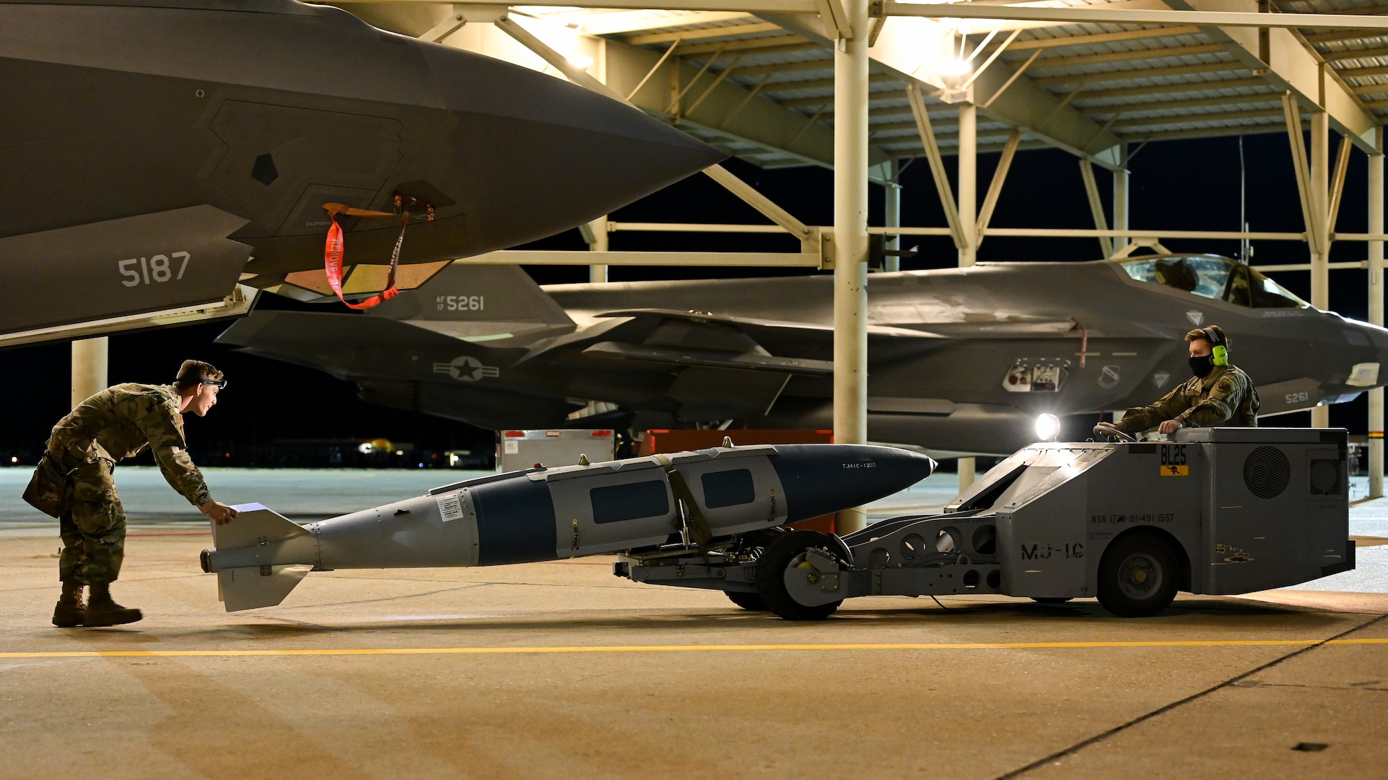 A photo of maintainers loading weapons onto and F-35A Lightning II.