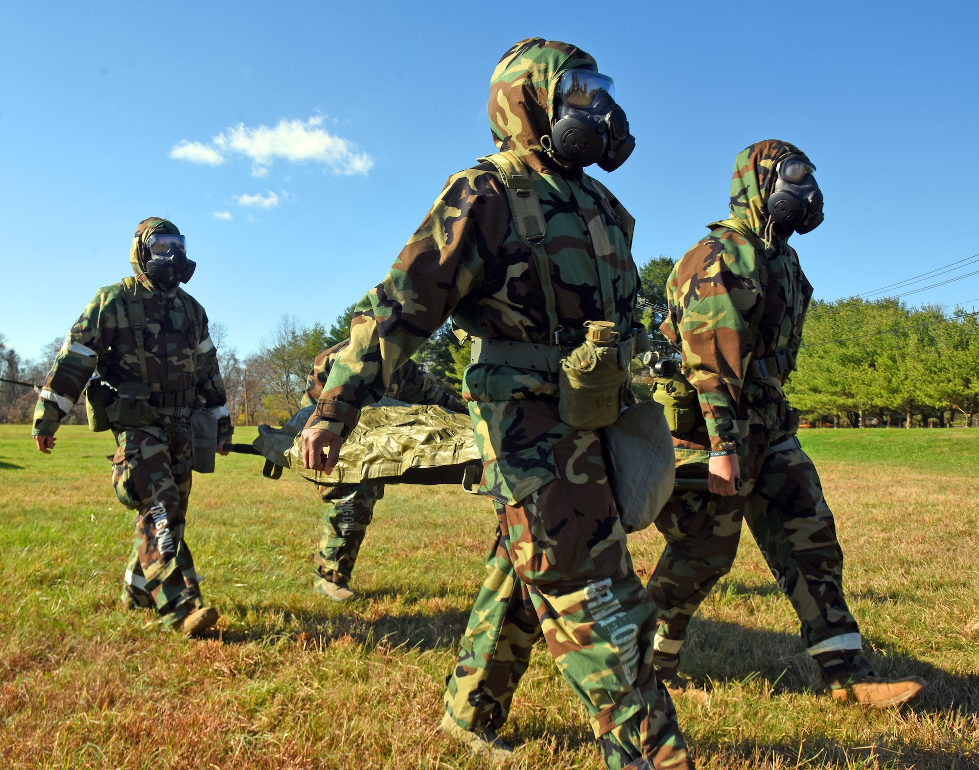 Participants transport a mock patient while wearing Mission Oriented Protective Posture gear during MEDEVAC tactical combat casualty care training at the Babe Ruth field, Nov. 16, 2020 on Joint Base McGuire-Dix-Lakehurst, N.J. Airmen must wear personal protection equipment while performing MEDEVAC tasks to practice safety procedures and prevent further casualties. (U.S. Air Force photo by Daniel Barney)