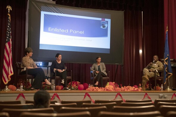 Four women sit in chairs on stage to answer audience questions.