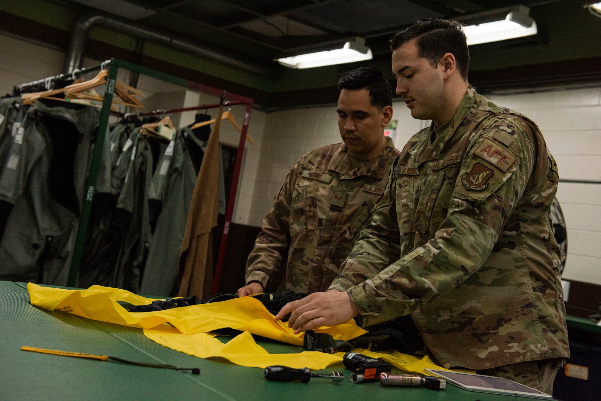 Two Airmen pack a life preserver unit