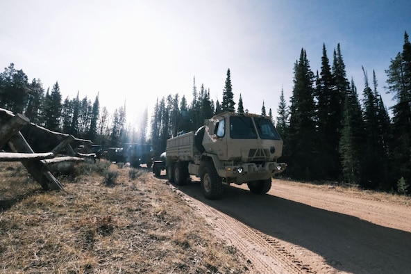 The 729th Air Control Squadron conducts convoy training with big military vehicles driving on a dirt road.