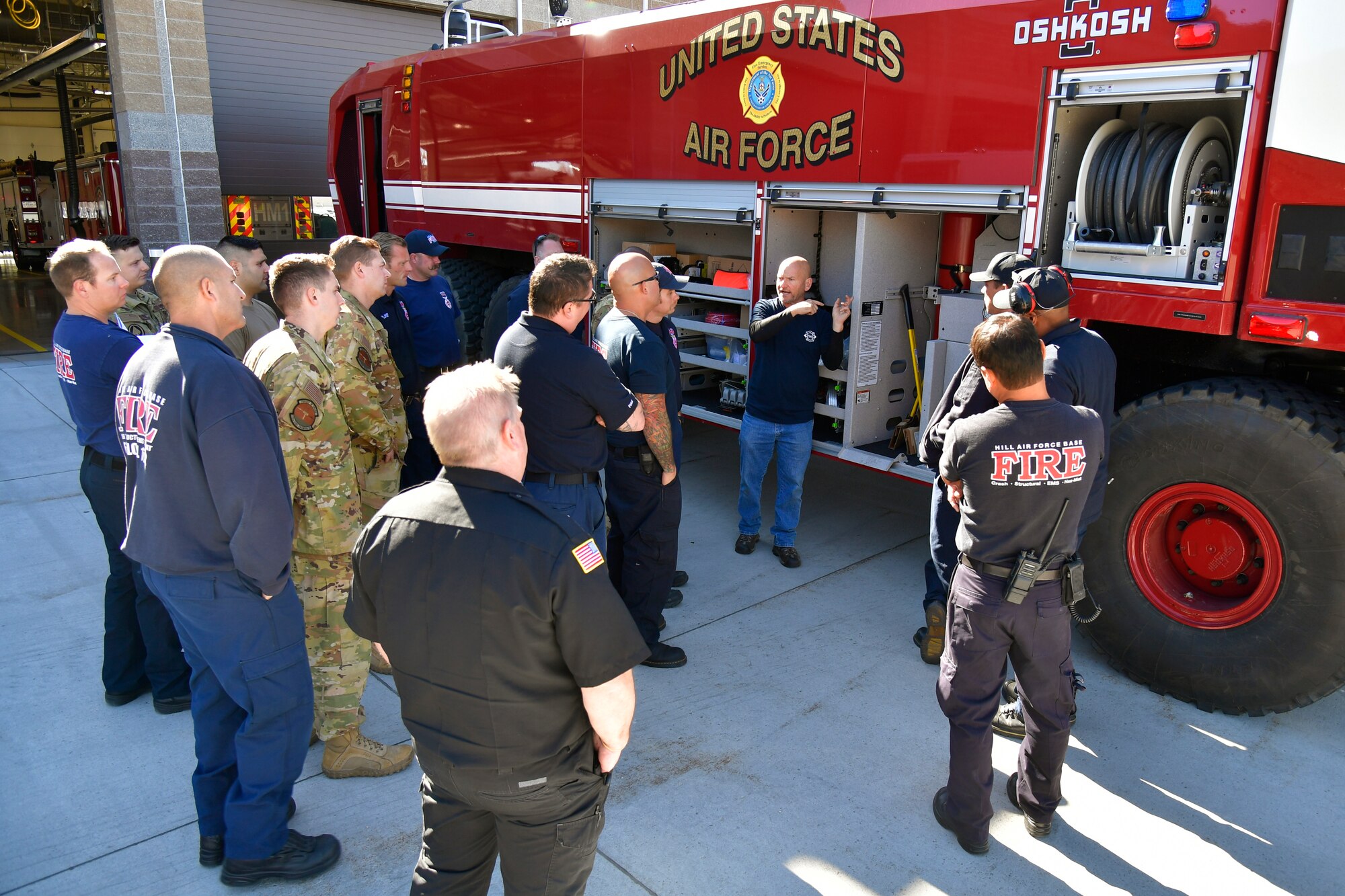 Firefighters and others standing around the crash/fire response vehicle.