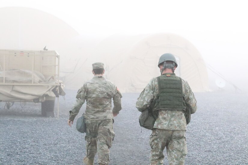 A 28th Infantry Division soldier (left) and a Lithuanian Land Forces soldier walk through an early morning fog in the division’s forward operating base, erected for the two-week Warfighter 21-2 exercise at Fort Indiantown Gap on Nov. 11 (U.S. Army photo Master Sgt. Daniel Palermo)