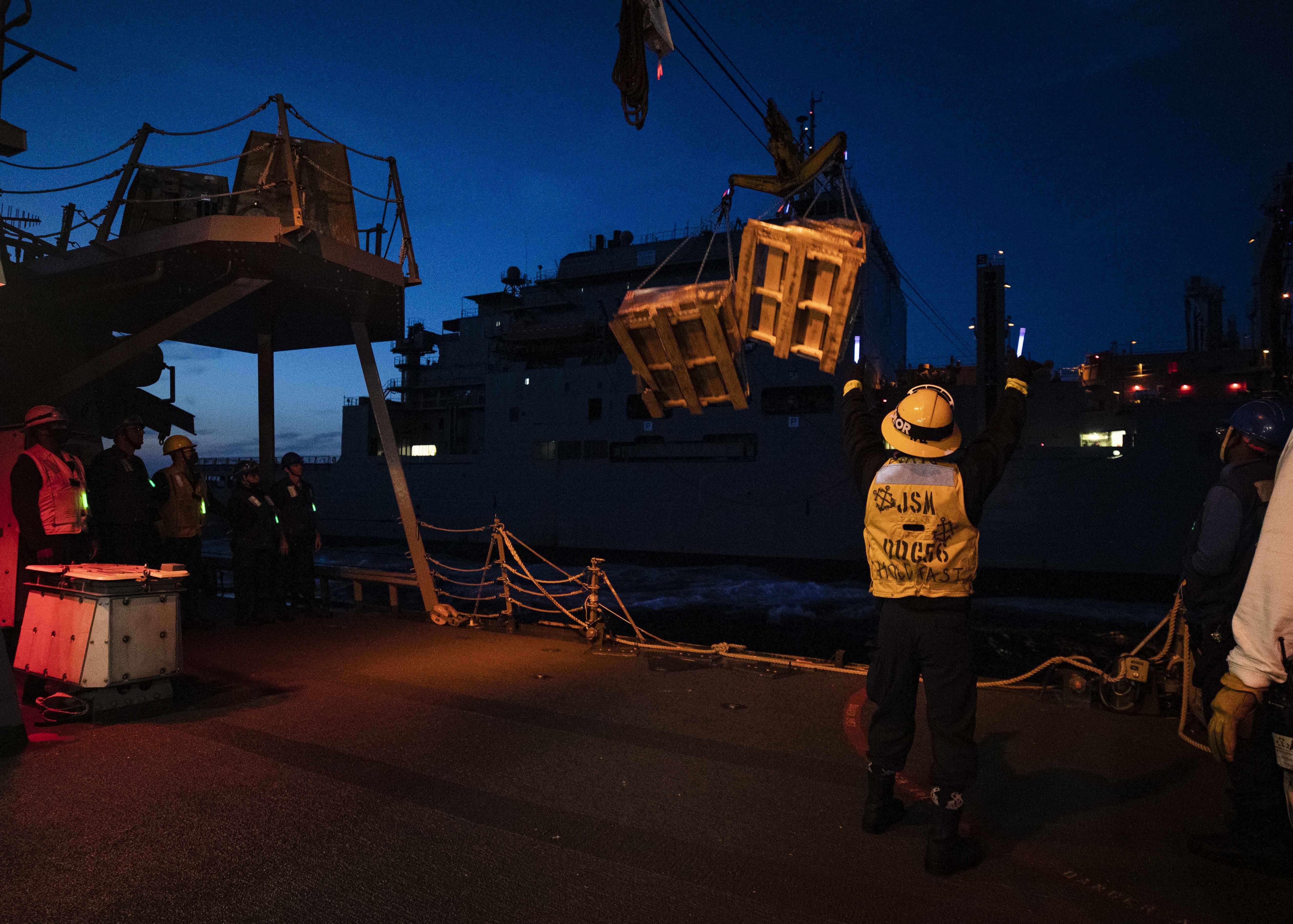 A Sailor receives cargo aboard the Arleigh Burke-class guided-missile destroyer USS John S. McCain (DDG 56) from the Lewis and Clark-class dry cargo and ammunition ship USNS Charles Drew (T-AKE 10) during a replenishment-at-sea.