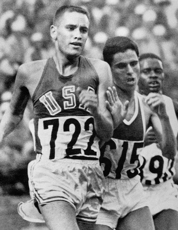 A black and white photo of three men racing on a track.