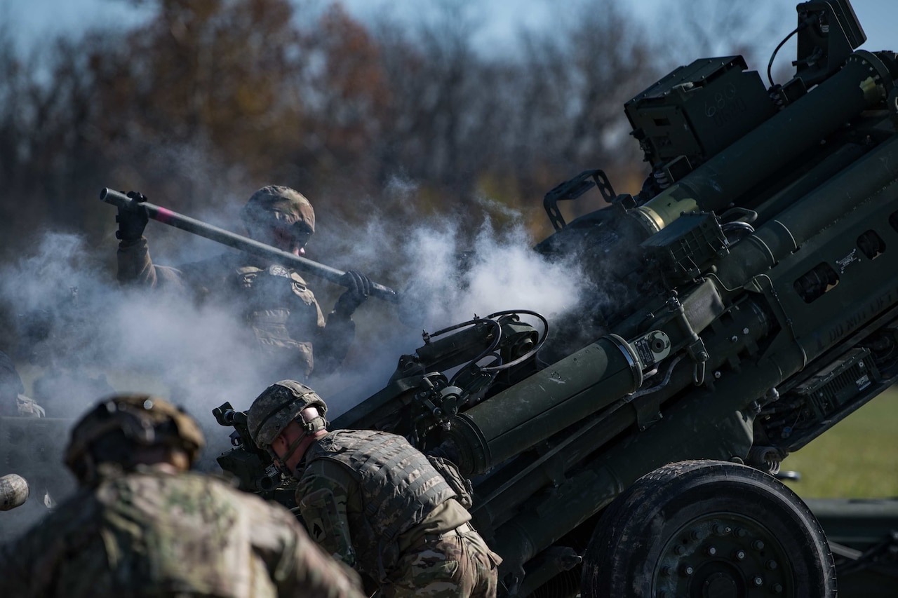 Soldiers reload an artillery piece after firing.