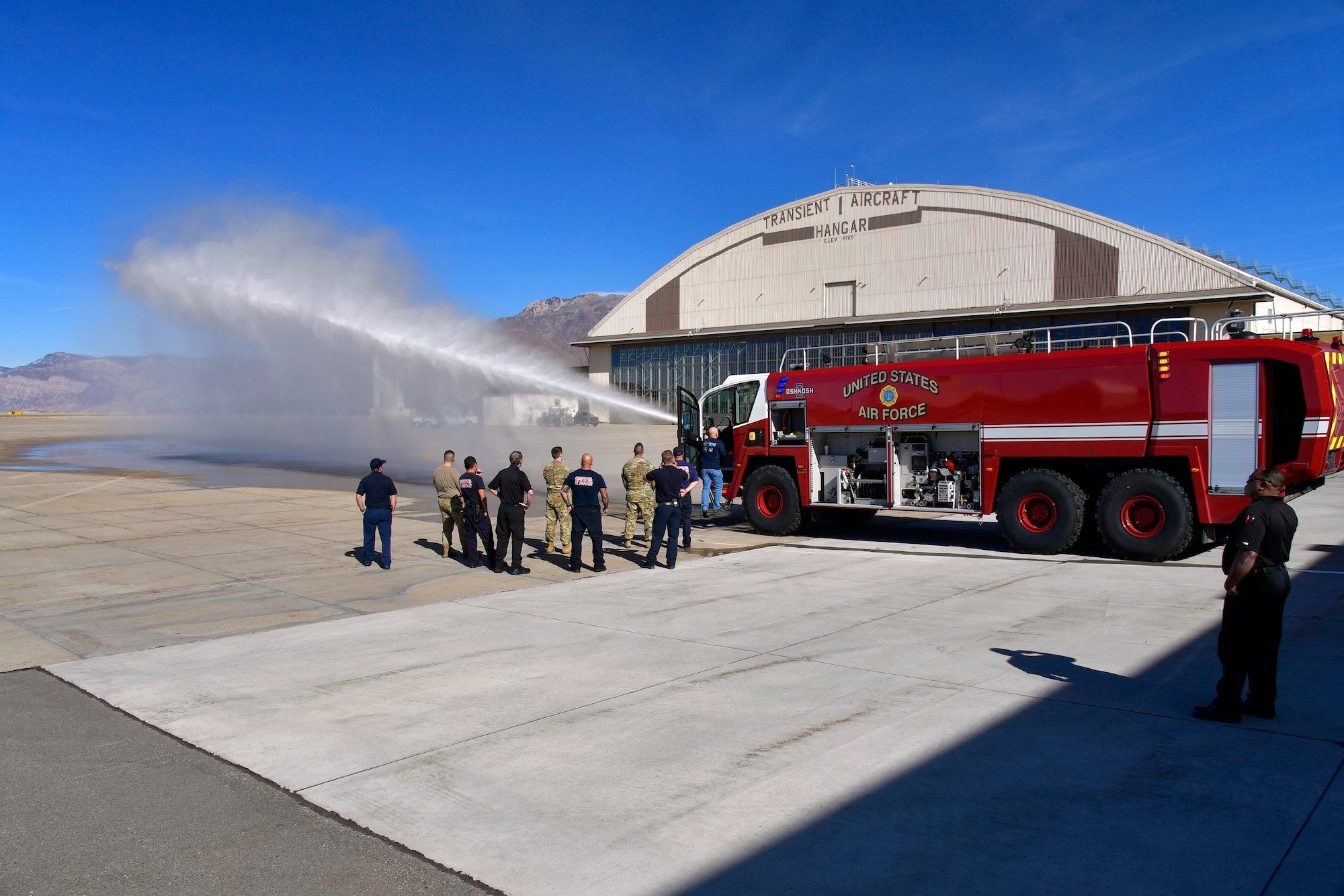 Firefighters watch as the water cannon attached to a newly delivered crash/fire response vehicle sprays water.